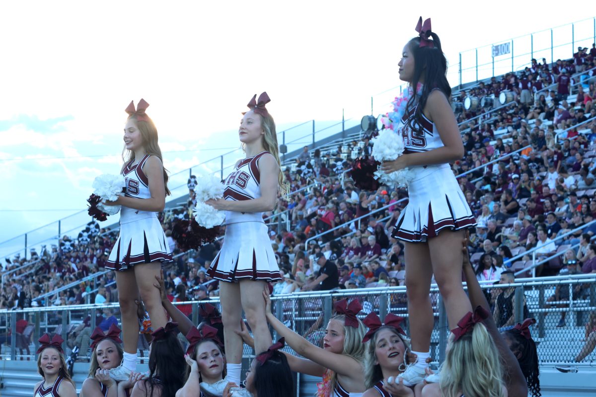 Abigail Jackson, Galilee Gresser, and Helena Tran Perform stunts at the varsity football game against JJ Pearce.